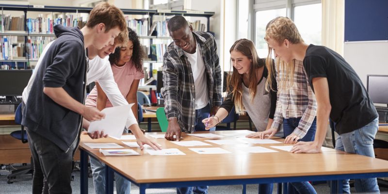 Group Of College Students Collaborating On Project In Library